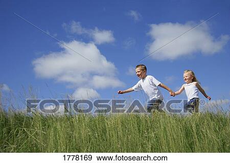 Boy & girl running in tall grass View Large Photo Image Stock Photo - Boy & girl running in tall grass. Fotosearch