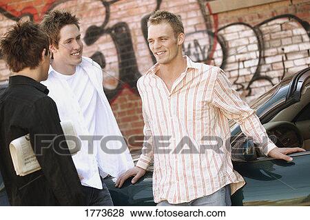 Stock Photo - Group of guys hanging out near car. Fotosearch