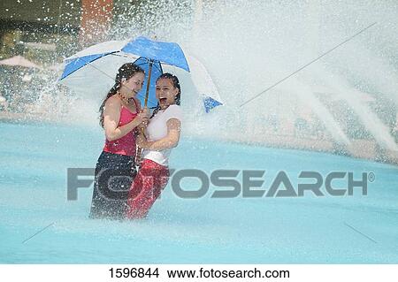 Picture - Two friends sharing an umbrella. Fotosearch