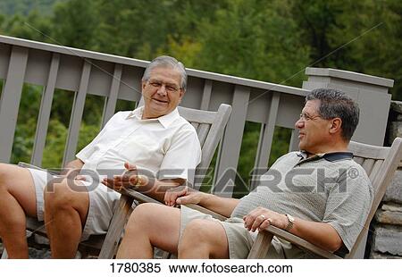 Stock Photography - Two men chat on patio. Fotosearch
