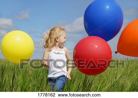 Stock Image - A child holding colorful balloons. Fotosearch