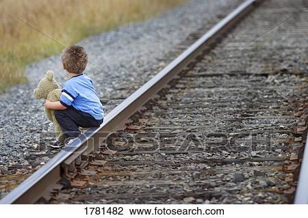 Child sits on train track View Large Photo Image Stock Image - Child sits on train track. Fotosearch