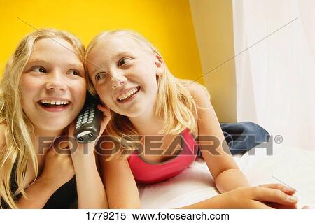 Stock Photography - Girls listen on phone. Fotosearch