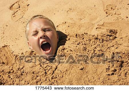 Stock Image - Young boy covered in sand. Fotosearch