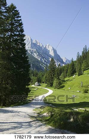Stock Photo - Alpine landscape with walking path winding through the valley. Fotosearch