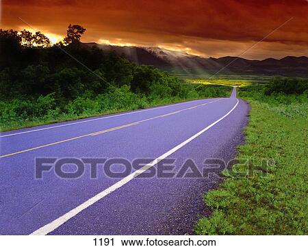 Stock Image - Country road on cloudy day. Fotosearch