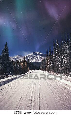Stock Image - Northern lights over a snowy road. Fotosearch
