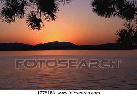 Stock Photo - A beautiful sunset over a body of water. Fotosearch