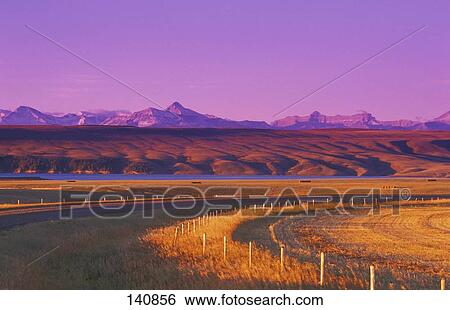 Stock Photograph - Farmer's field with river and mountains in background and road in foreground. Fotosearch