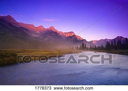 Stock Image - Sunrise and early morning mist on river Elk Lakes. Fotosearch