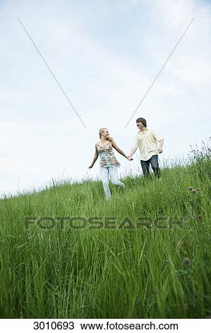 A young couple walking through a meadow, low angle view View Large Photo Image Stock Image - A young couple walking through a meadow, low angle view . Fotosearch