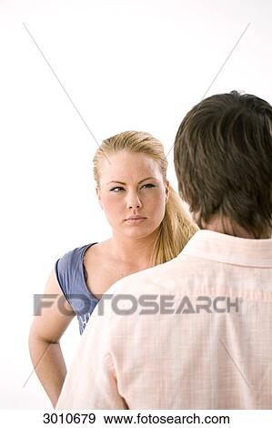 Stock Photo - A Young woman glaring at man, over the shoulder, studio shot . Fotosearch