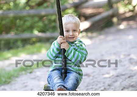 Blond boy sitting on a swing View Large Photo Image Stock Photograph - Blond boy sitting on a swing . Fotosearch