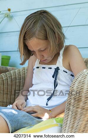 Picture - Blond girl sitting in wicker chair . Fotosearch