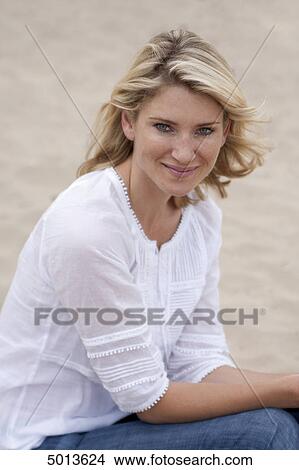 Blond woman sitting in sand View Large Photo Image Picture - Blond woman sitting in sand . Fotosearch