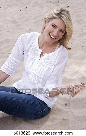 Blond woman sitting in sand View Large Photo Image Stock Image - Blond woman sitting in sand . Fotosearch