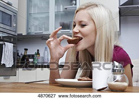 Stock Photo - Blond young woman eating pastry . Fotosearch