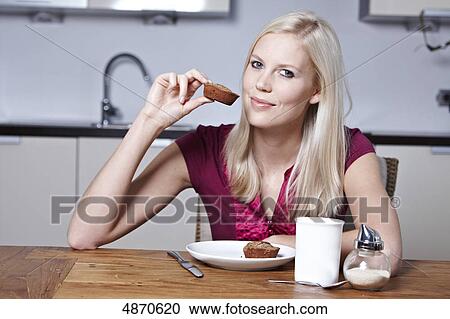 Stock Image - Blond young woman holding pastry . Fotosearch
