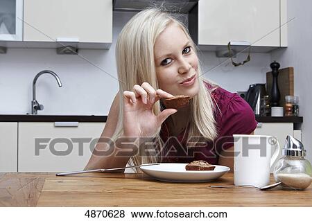 Stock Photo - Blond young woman holding pastry . Fotosearch