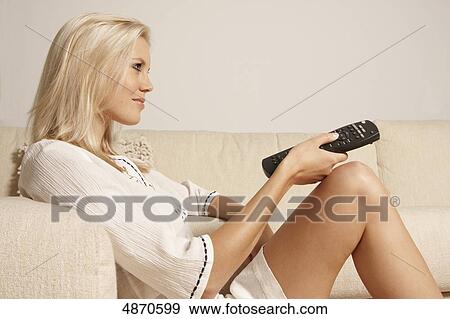 Blond young woman holding remote control View Large Photo Image Stock Photo - Blond young woman holding remote control . Fotosearch