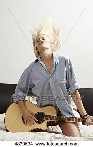 Picture - Blond young woman playing guitar . Fotosearch