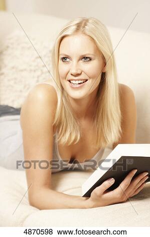 Blond young woman reading book on couch View Large Photo Image Stock Photo - Blond young woman reading book on couch . Fotosearch