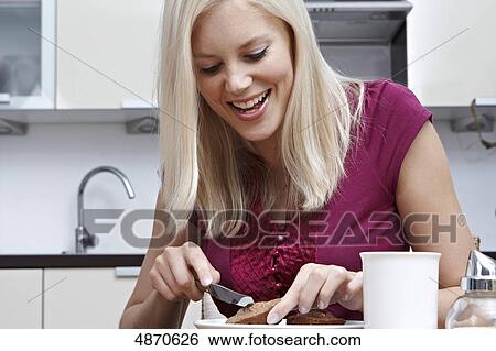 Stock Photograph - Blond young woman slicing pastry . Fotosearch