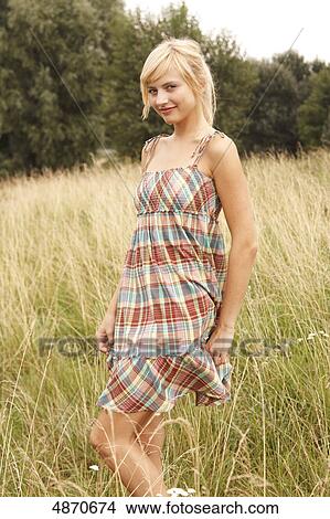 Blond young woman standing in meadow View Large Photo Image Picture - Blond young woman standing in meadow . Fotosearch