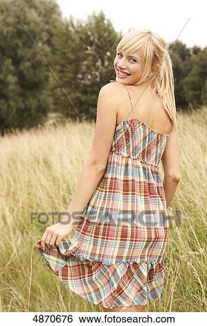 Stock Photograph - Blond young woman standing in meadow . Fotosearch
