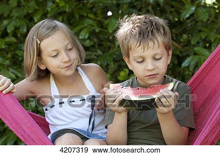 Boy and girl sitting in hammock, boy eating melon View Large Photo Image Stock Photo - Boy and girl sitting in hammock, boy eating melon . Fotosearch