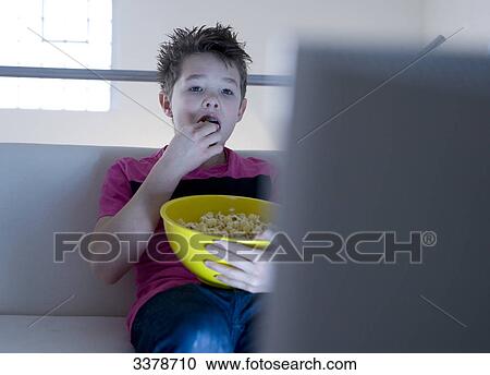 Boy eating popcorn and watching TV View Large Photo Image Stock Image - Boy eating popcorn and watching TV . Fotosearch