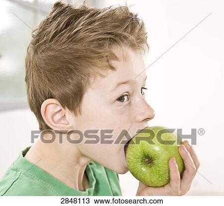 Stock Image - Boy having granny smith apple . Fotosearch