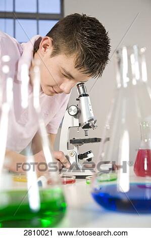 Stock Image - Boy looking through microscope in chemistry laboratory . Fotosearch
