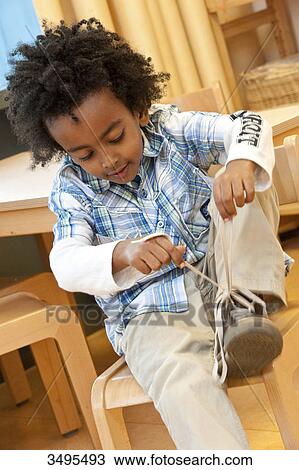 Stock Image - Boy tying his shoelace . Fotosearch