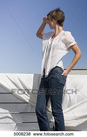 Stock Photo - Brunette woman looking under blue sky . Fotosearch