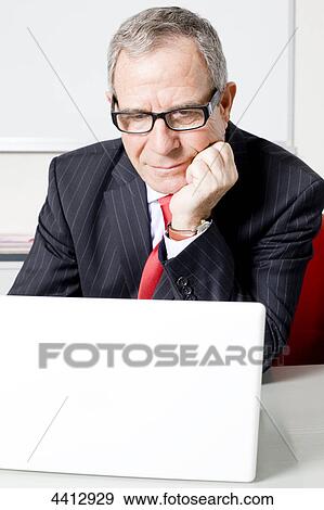 Stock Photo - Businesman sitting on front of laptop . Fotosearch