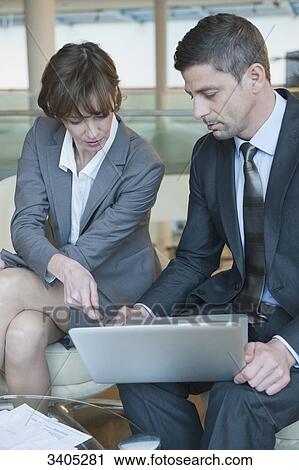 Stock Image - Business woman and business sitting at laptop . Fotosearch