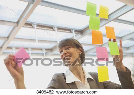 Business woman sticking post-its on a glass pane View Large Photo Image Stock Image - Business woman sticking post-its on a glass pane . Fotosearch