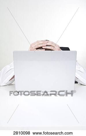 Stock Photo - Businessman holding his head in front of laptop . Fotosearch
