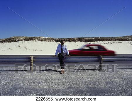 Businessman leaning against railing at roadside View Large Photo Image Stock Photography - Businessman leaning against railing at roadside . Fotosearch