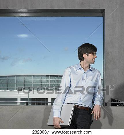Stock Photo - Businessman leaning against wall and smiling . Fotosearch