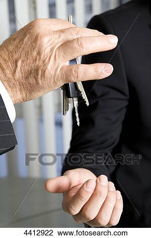 Stock Image - Businessman passing key . Fotosearch