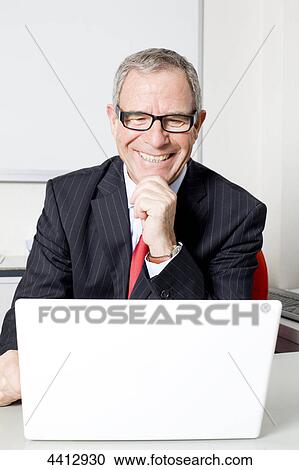 Businessman sitting in front of laptop View Large Photo Image Stock Image - Businessman sitting in front of laptop . Fotosearch