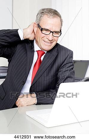 Businessman sitting in front of laptop View Large Photo Image Stock Image - Businessman sitting in front of laptop . Fotosearch