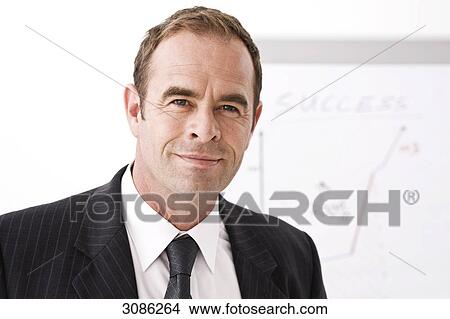 Businessman standing in front of a flip chart, facing camera, close-up View Large Photo Image Picture - Businessman standing in front of a flip chart, facing camera, close-up . Fotosearch