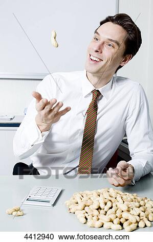 Stock Image - Businessman throwing peanut . Fotosearch