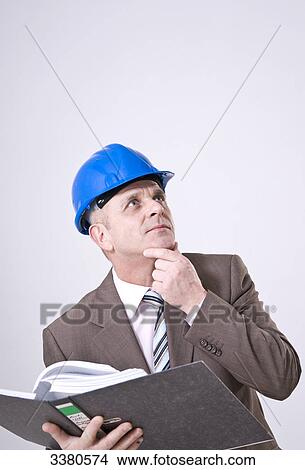 Picture - Businessman wearing hard hat, holding filing folder . Fotosearch