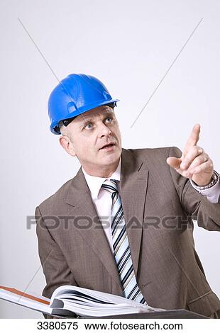 Stock Photography - Businessman wearing hard hat, holding filing folder . Fotosearch