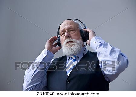 Stock Image - Businessman wearing headphones and listening to music . Fotosearch