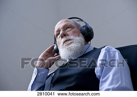 Stock Image - Businessman wearing headphones and listening to music . Fotosearch
